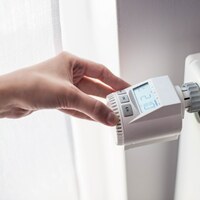 Woman's hand adjusting temperature on home wall heater